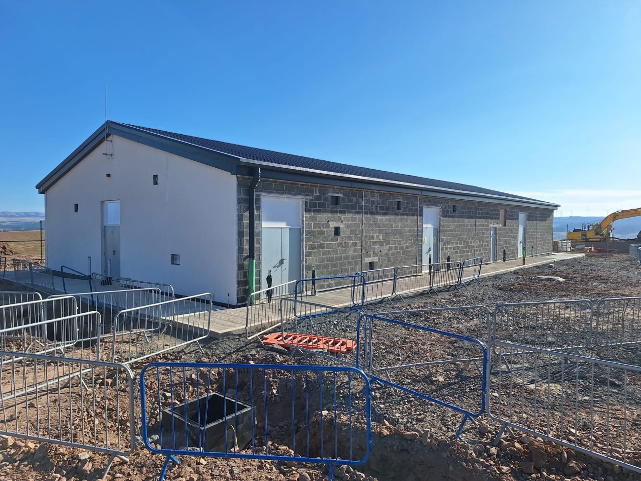 The newly completed control building at Hagshaw Hill Windfarm, finished with render, cladding and blockwork external walls under a clear blue sky. 